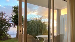 A sliding glass door leading to an outdoor patio with wicker furniture and a view of the sea.