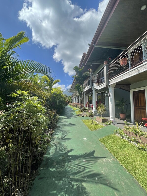 A pathway flanked by lush greenery and traditional architecture.