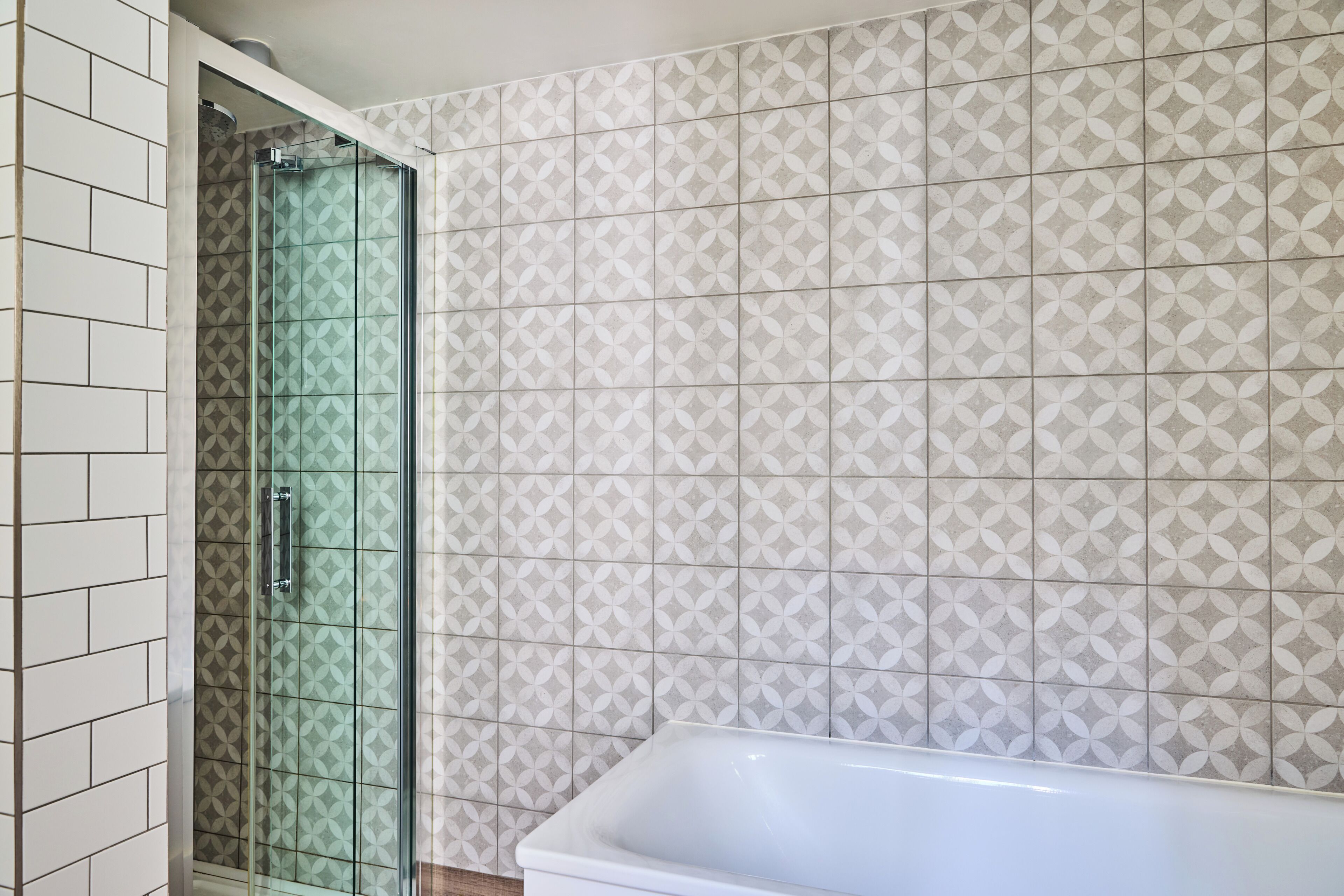 A bathroom with a glass shower enclosure and a white bathtub.