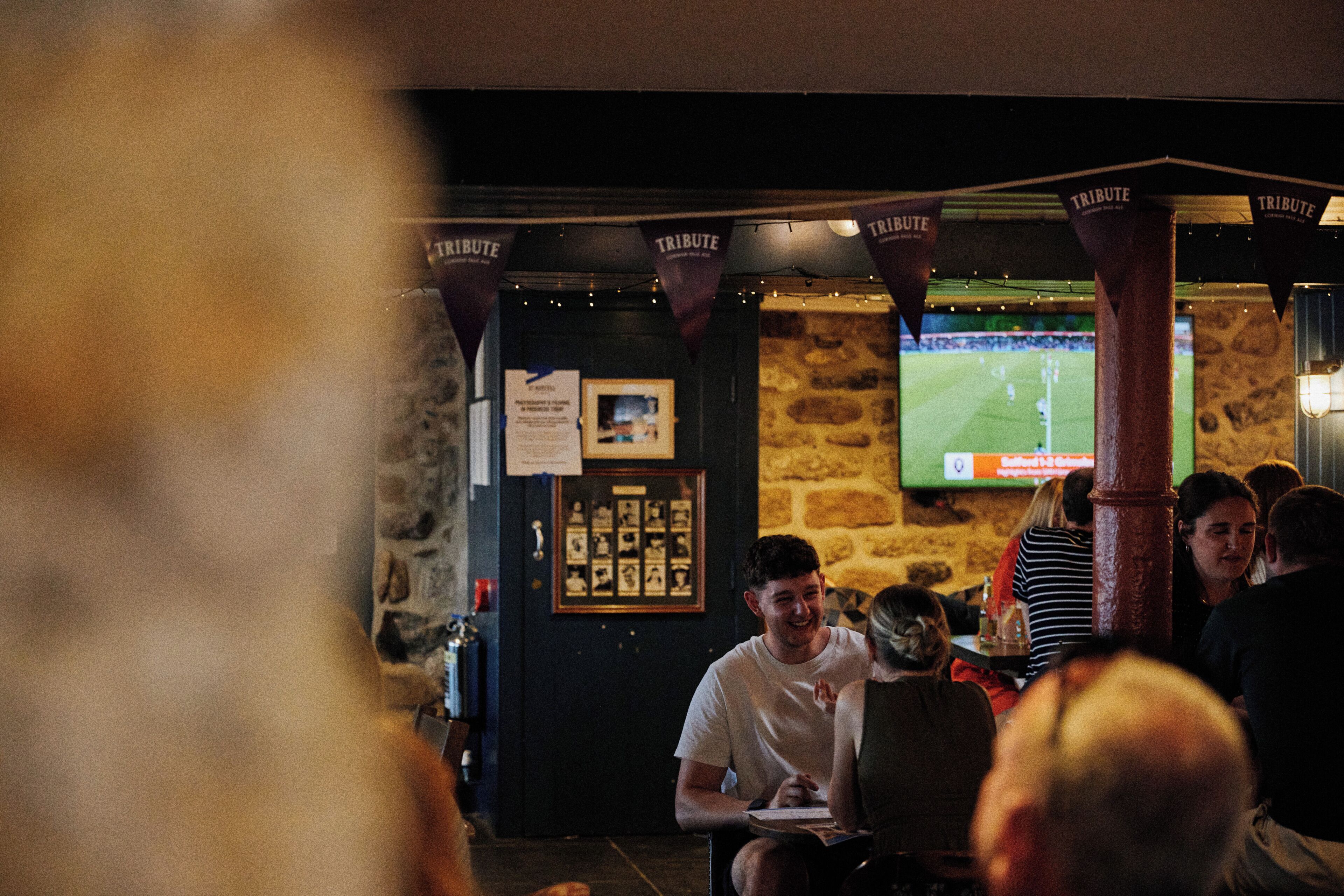 A bar with stone walls, a television screen, and hanging banners.