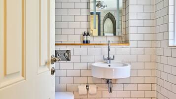 A bathroom with a white sink, a toilet, and a mirror above the sink.