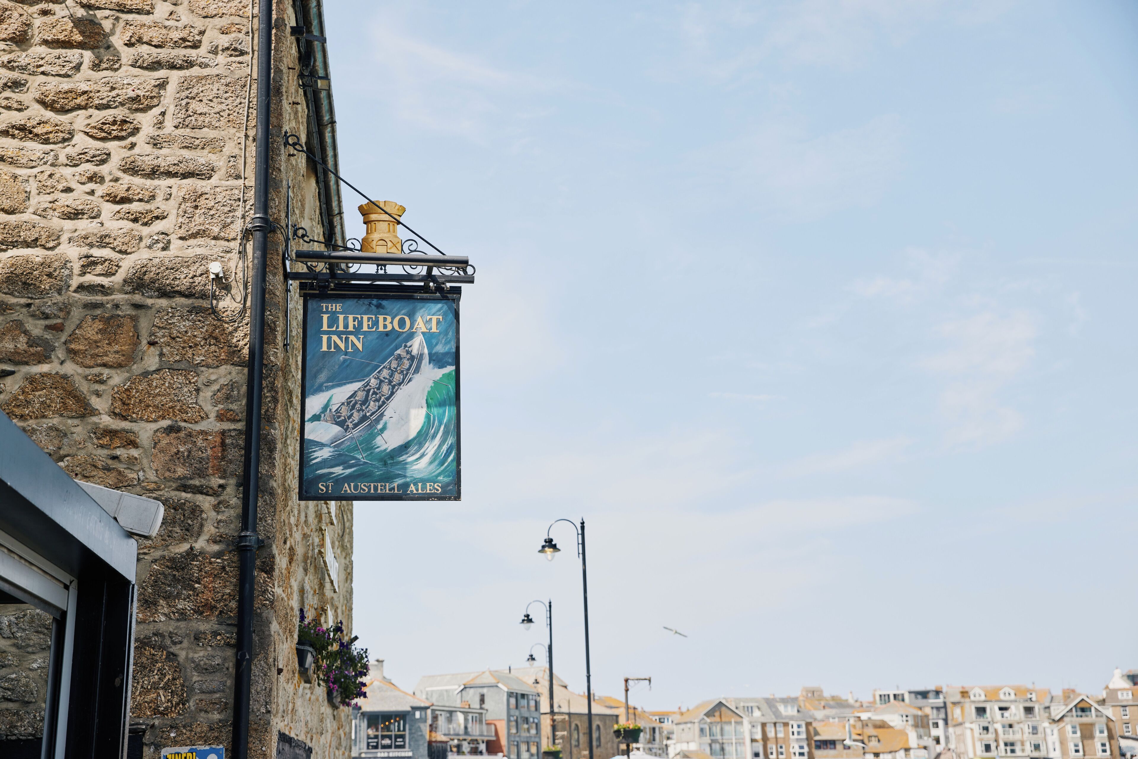 Ein Steinhaus mit einem Schild, das 'The Lifeboat Inn' zeigt und eine Illustration eines Segelboots enthält.