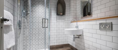 Un baño moderno con ducha envuelta en vidrio, lavabo blanco y retrete.