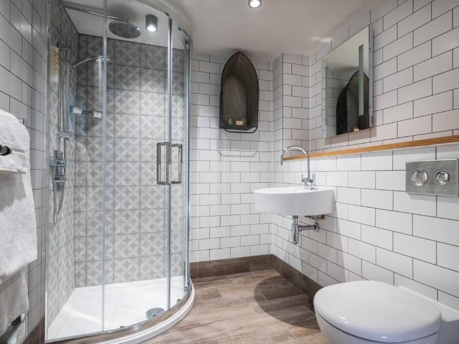 A modern bathroom with a glass-enclosed shower, a white sink, and a toilet.