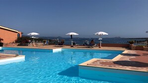 A clear blue swimming pool with sun loungers and umbrellas, surrounded by a stone wall and overlooking the sea. - Casa Azul, Seaview terrace, private parking, pool (Golfo Aranci)