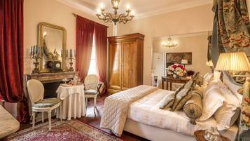 A bedroom with a large bed, a wooden wardrobe, a mirror, and a chandelier.