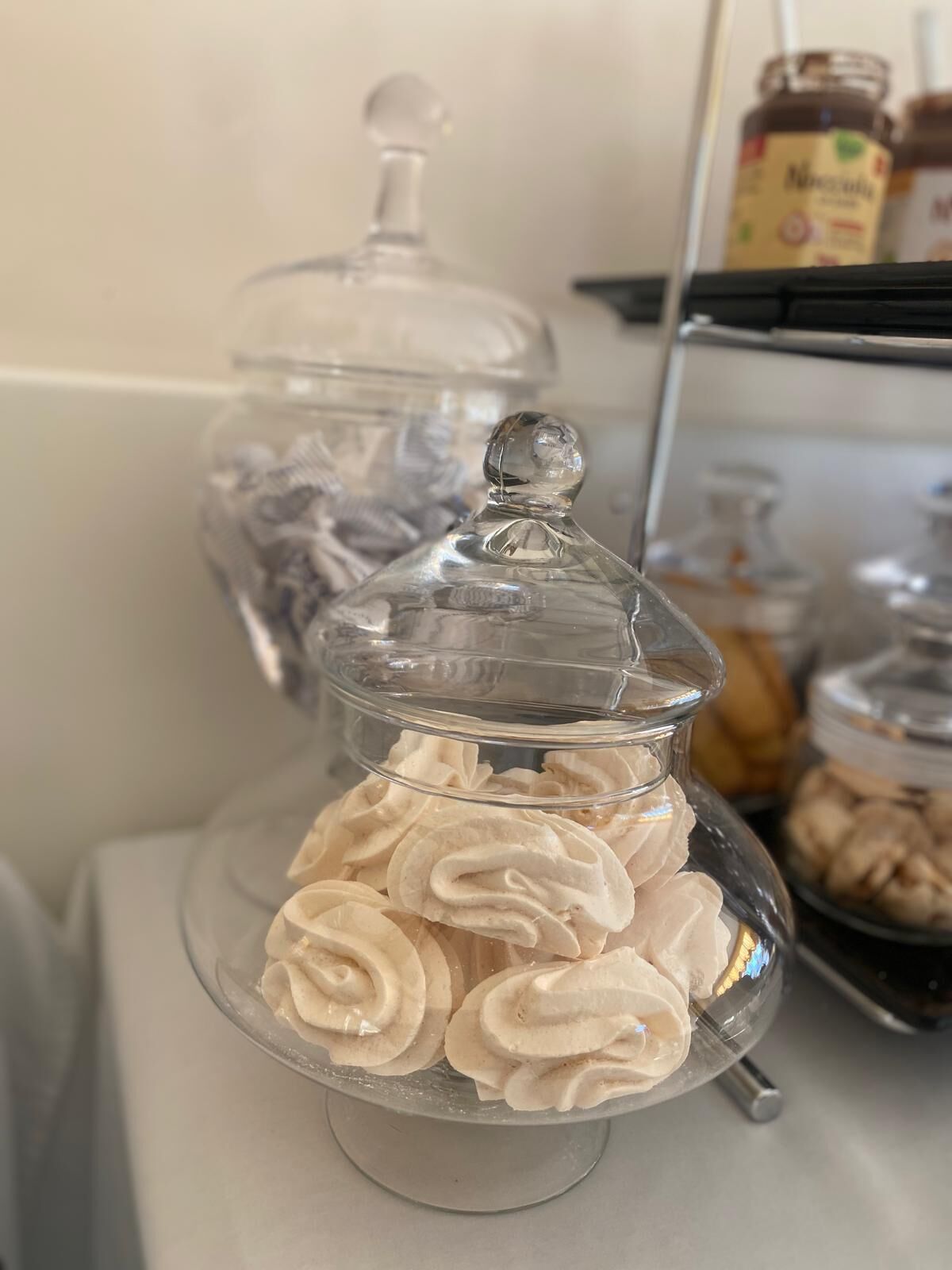A glass display case with a lid, containing white swirled pastries.