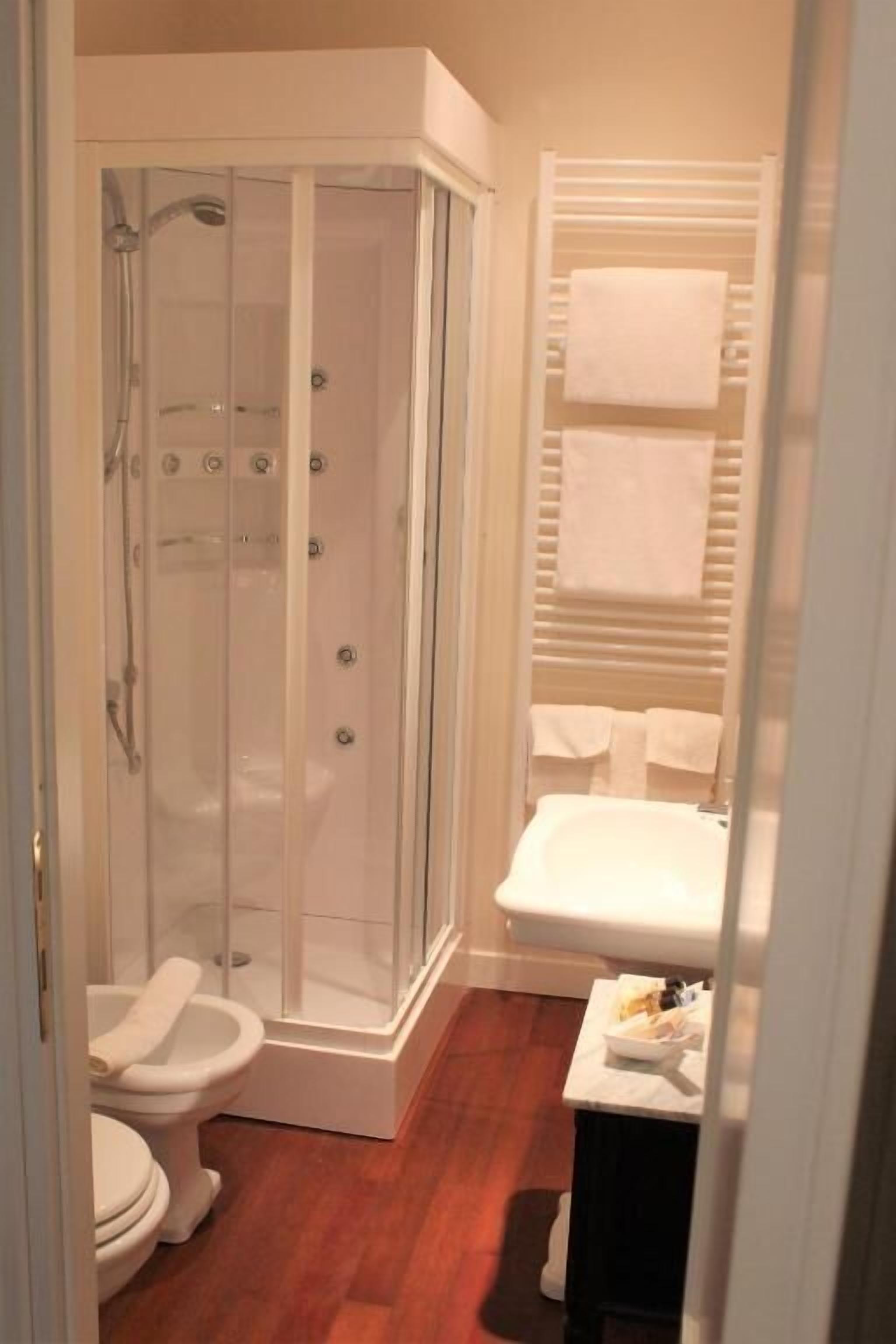 Un baño con ducha de vidrio, inodoro, lavamanos y perchero para toallas.