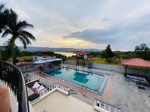 A pool area with a view of the mountains and a lake. - H2O Greens Villa Near Pune (Mawal)
