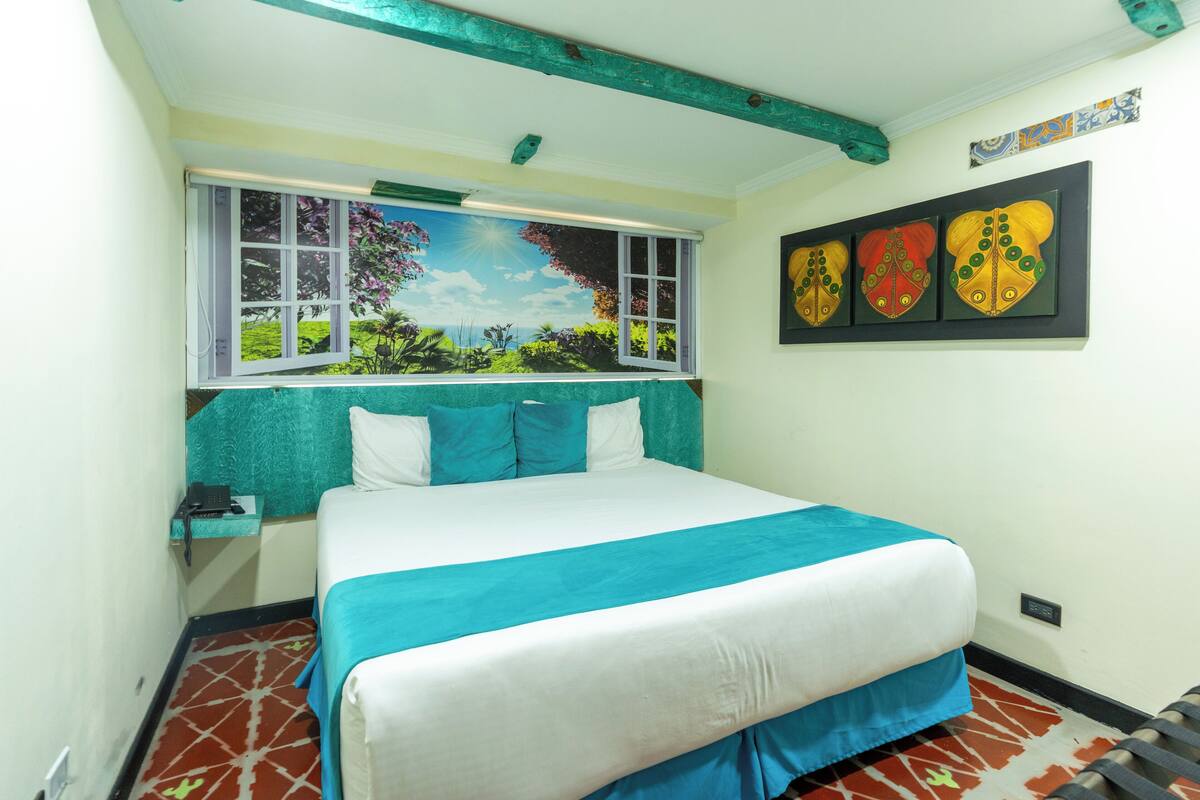 Une chambre à coucher avec un lit, une fenêtre donnant sur un paysage verdoyant et trois éléments décoratifs fixés au mur.