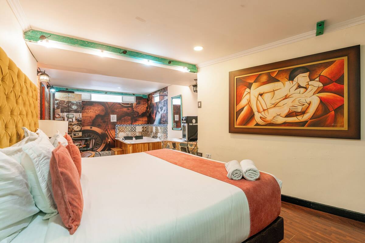 Une chambre d’hôtel avec un lit, un tableau et une salle de bain visible au fond.