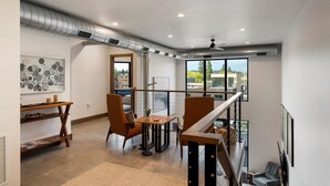 A modern living room with a dining area, large windows, and a view of the city.