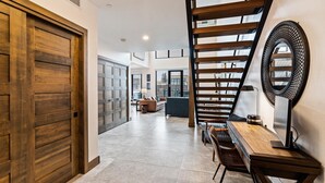 A modern interior with a wooden staircase, a dining area, and a view of the outside.