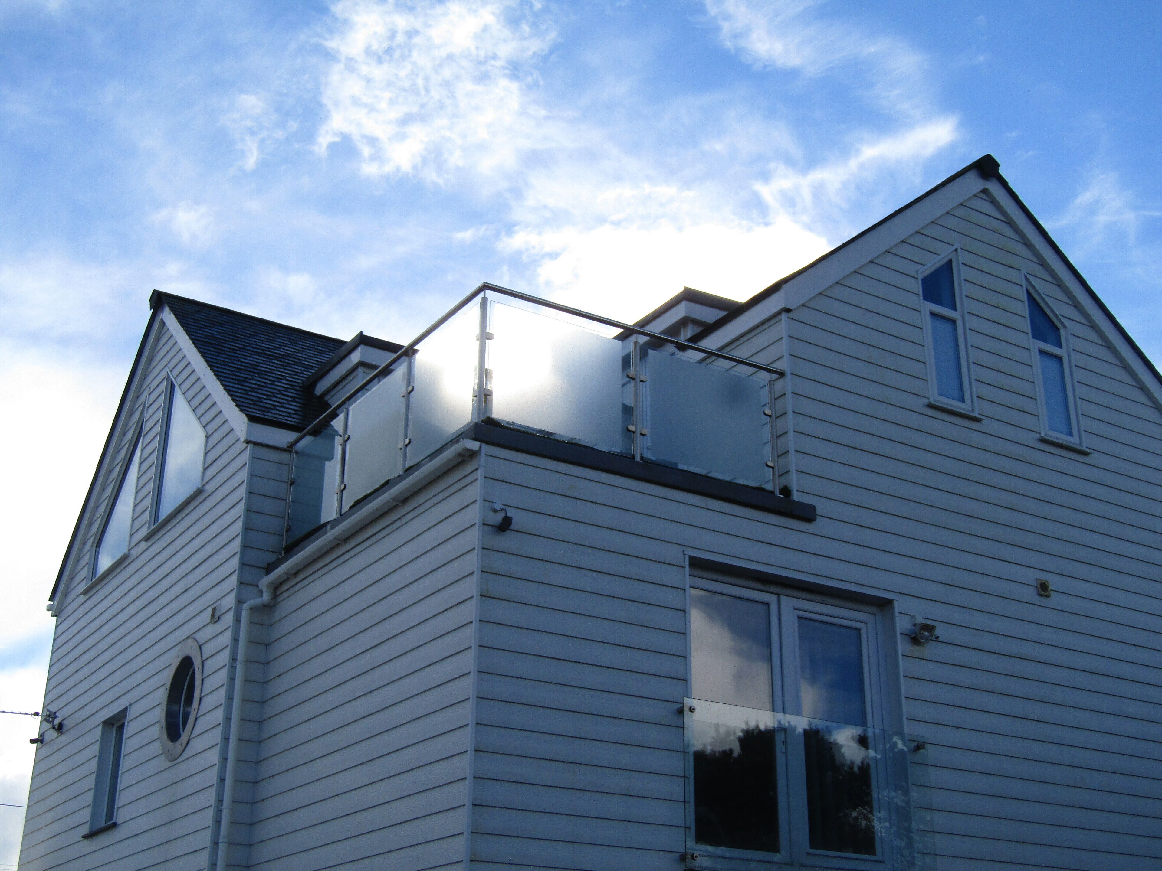 A two-story house with a gable roof, a dormer window, and a small balcony.