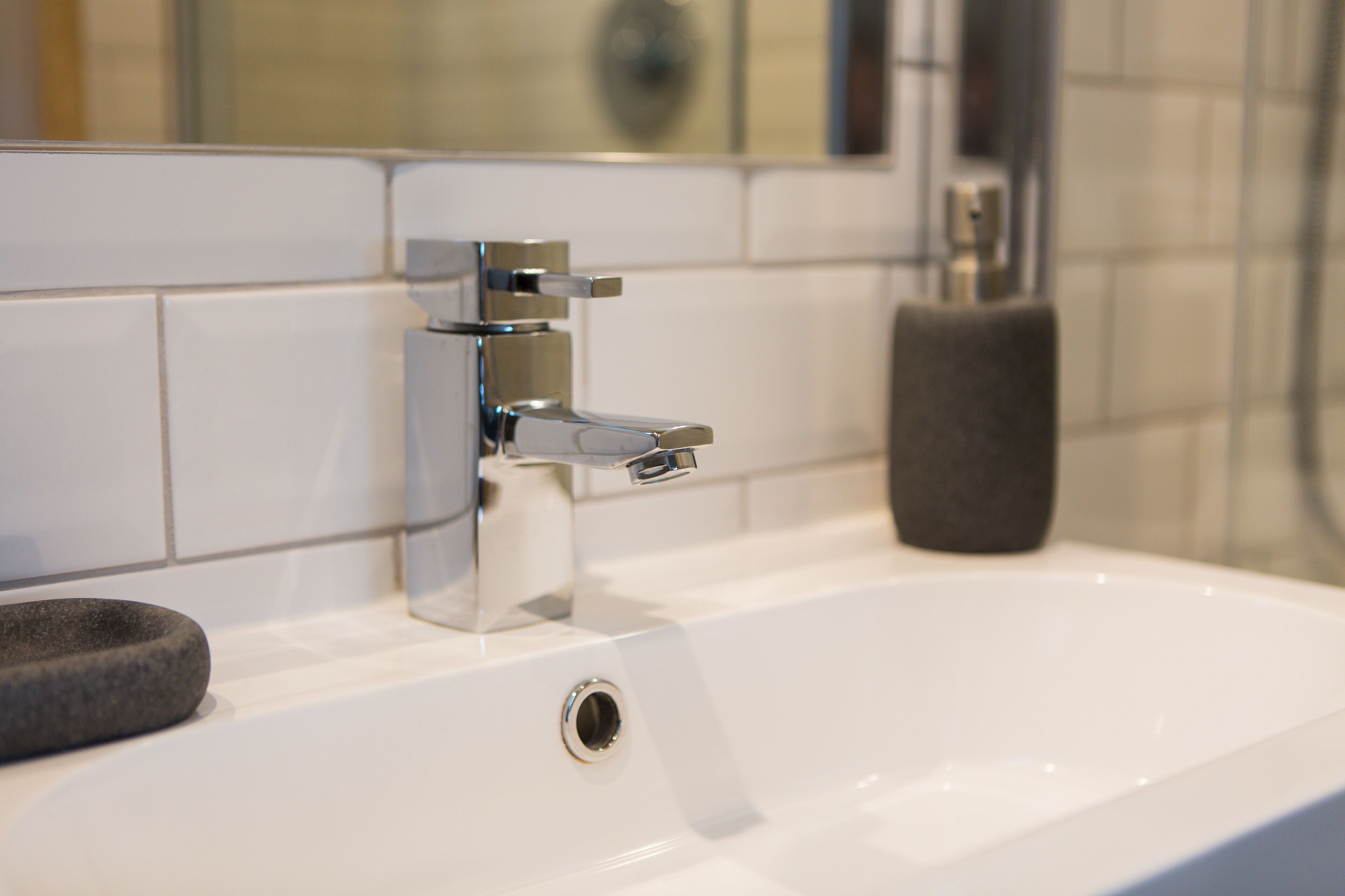 A bathroom sink with a chrome faucet, a soap dish, and a towel holder.