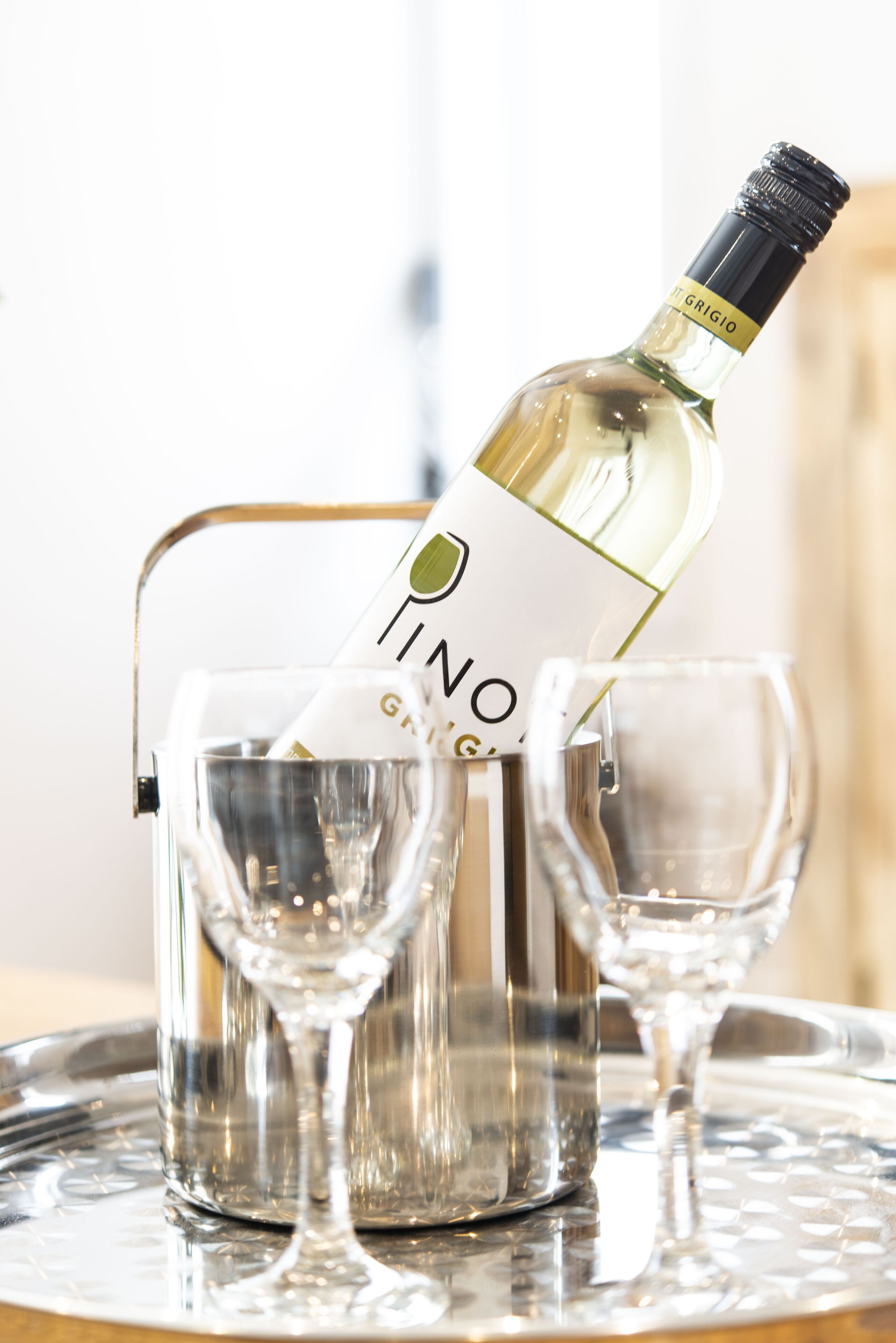 Une bouteille de vin dans un porte-bouteille, avec deux verres à côté.