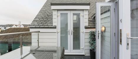 Een woongebouw met een balkon, een schuifpui en een bloempot.