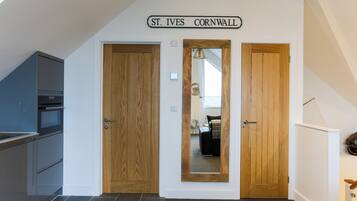 A hallway with two wooden doors, a kitchen area, and a sign reading "St. Ives Cornwall".