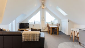 A modern loft apartment with a dining area, kitchen, and living space. - The Lighthouse (St Ives)