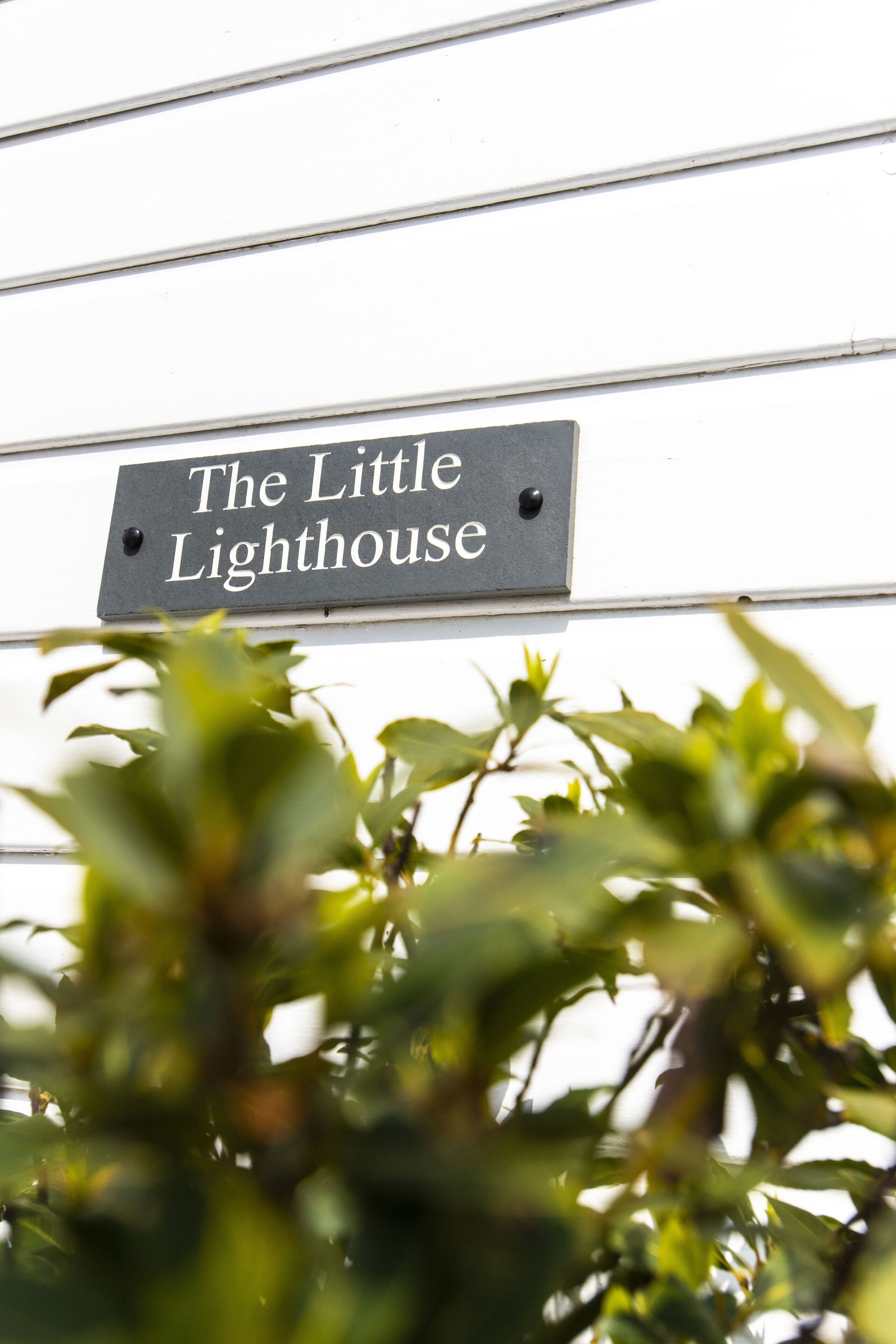 A sign reading "The Little Lighthouse" mounted on a white wall.