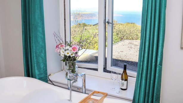 A room with a large window, a vase of flowers, a bottle of wine, and a tray with glasses. - Voebroch (Whitby)