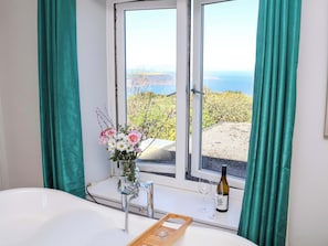 A room with a large window, a vase of flowers, a bottle of wine, and a tray with glasses. - Voebroch (Whitby)