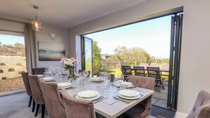 A dining area with a table set for six, large windows, and a view of the outdoors. - Voebroch (Whitby)