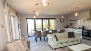 A modern kitchen with a dining area, a sofa, and a coffee table. - Voebroch (Whitby)