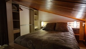 A bedroom with a bed, a nightstand, a lamp, and a wardrobe.