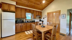 Cucina con mobili in legno, frigorifero bianco, fornello e tavolo da pranzo con sedie.