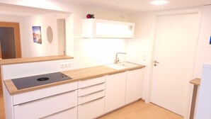 Una cocina compacta con armarios blancos, una encimera de madera, un lavamanos empotrado y una estufa.