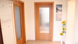 Un pasillo con una puerta de madera, un panel de vidrio esmerilado y un cuadro colgado en la pared.