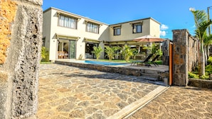 Un bâtiment à deux étages doté d’une terrasse en pierre et d’une piscine.