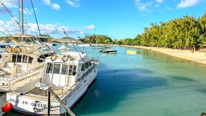 Un port de plaisance où sont amarrés plusieurs bateaux, une plage de sable et un ciel bleu dégagé.