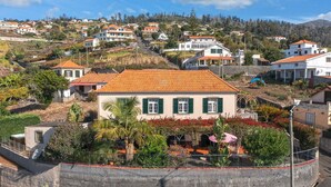 Un quartier résidentiel composé de maisons, dont certaines sont surmontées de toits en tuiles rouges, entouré de verdure et avec des collines en arrière-plan.