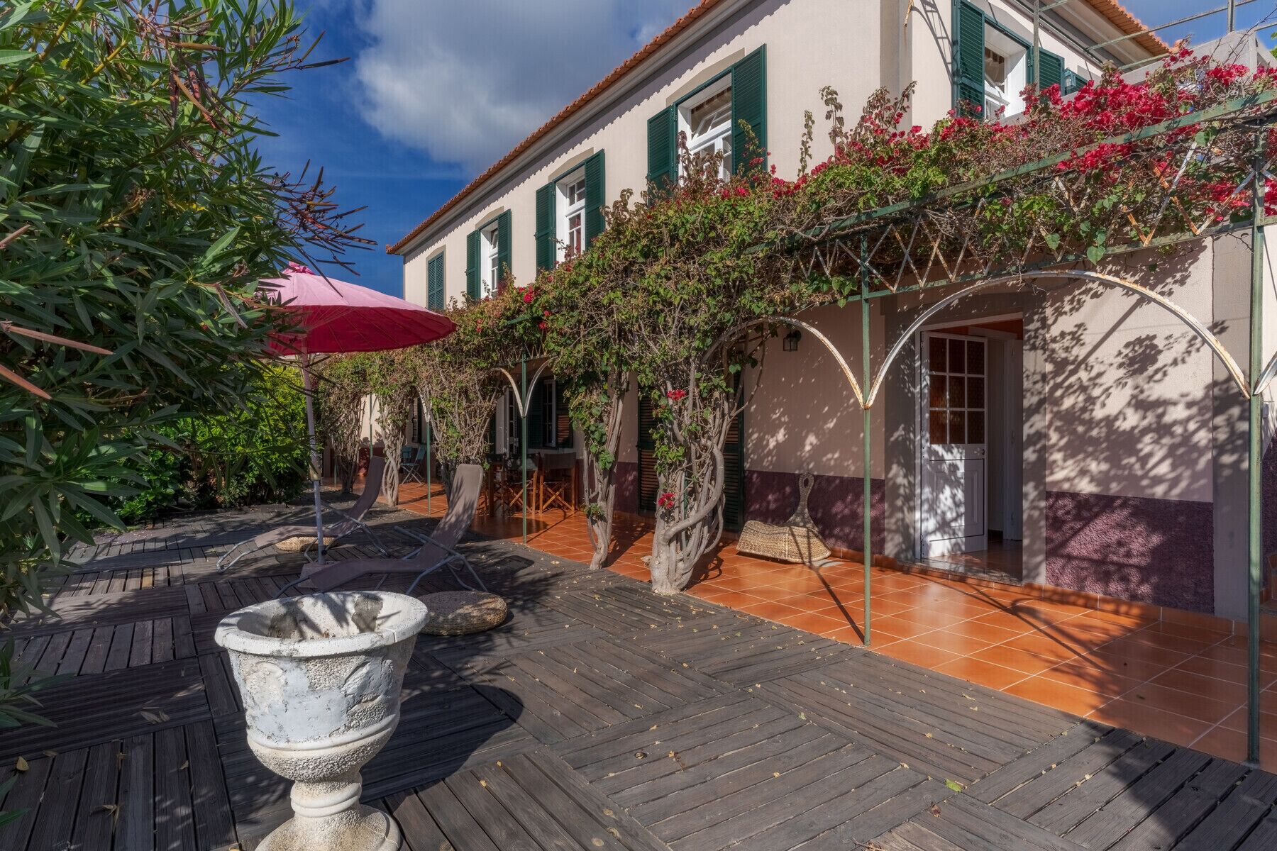 A courtyard with a pergola covered in climbing plants and a stone fountain.