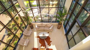 A high-ceilinged lounge area with a central seating arrangement, large windows, and potted plants. - ibis Styles Bonito (Bonito)