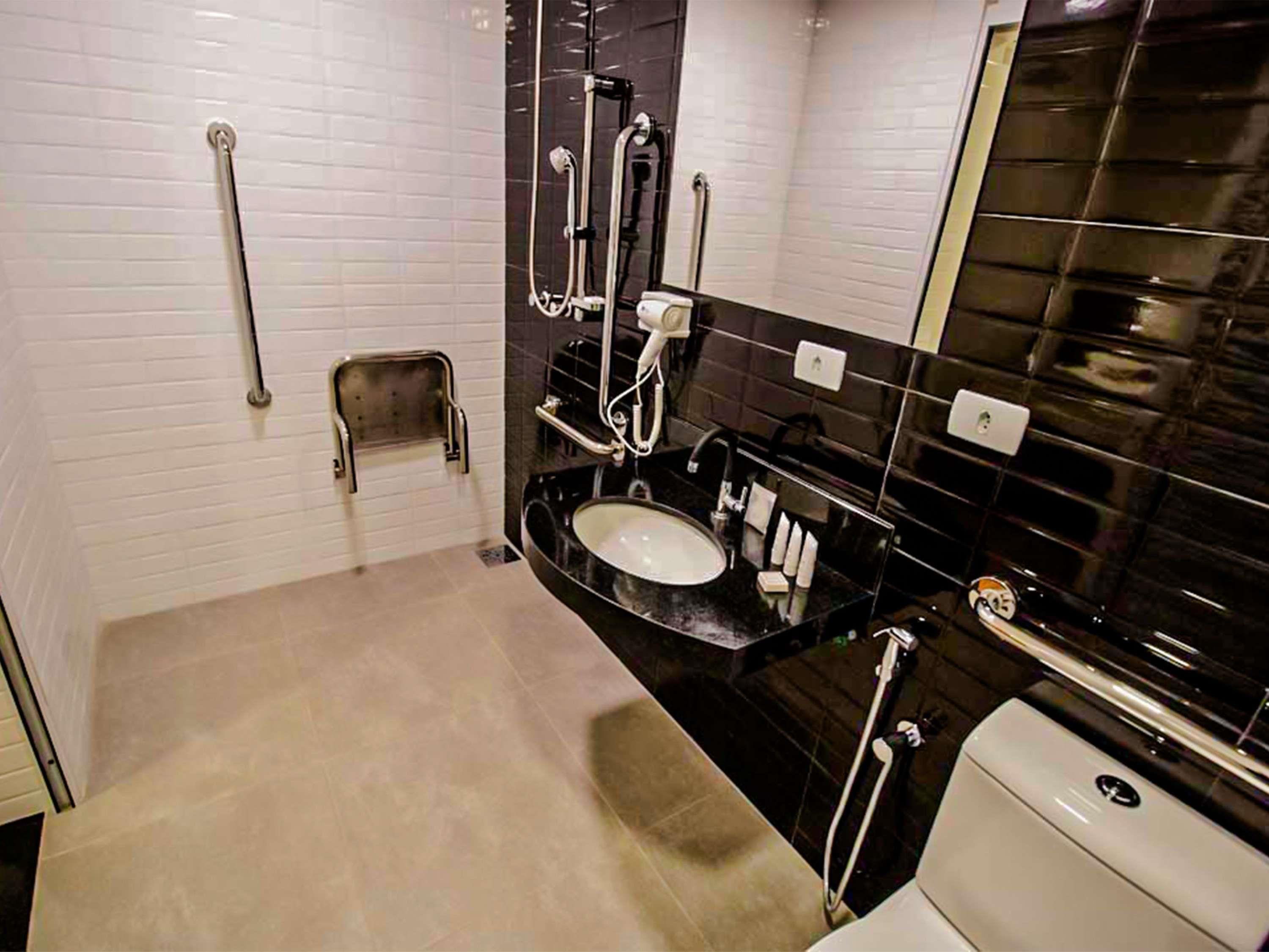 A modern bathroom with a white sink, black countertop, and a mirror.