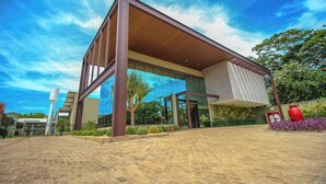 A modern building with a large glass facade, a prominent overhang, and a paved entrance area with landscaping. - ibis Styles Bonito (Bonito)