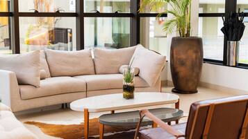 Una sala de estar moderna con un sofá color beige, una mesa de centro de vidrio y un sillón de cuero.