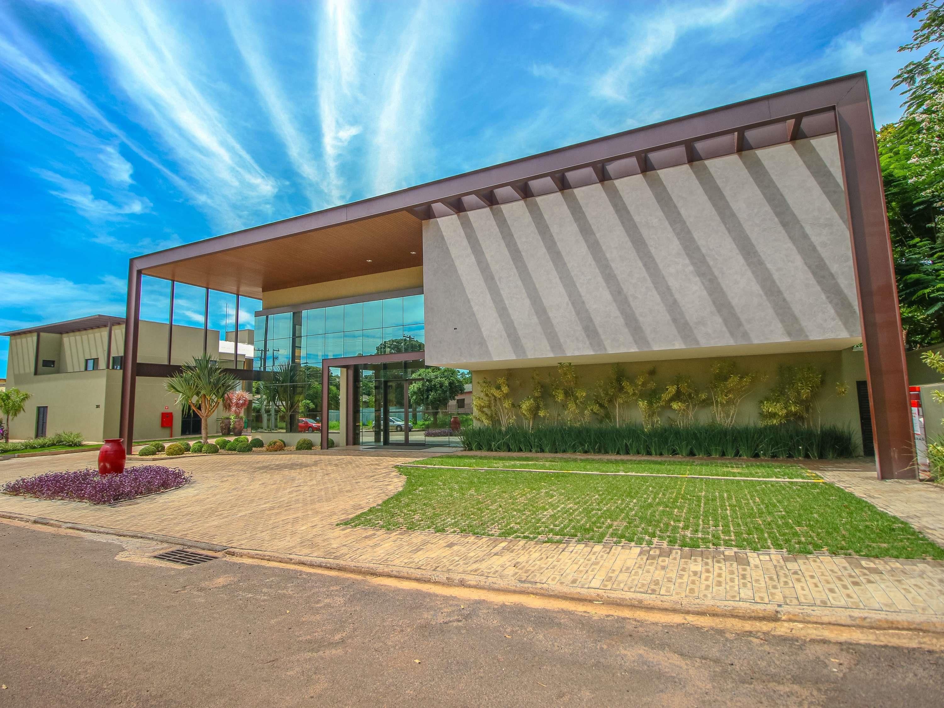 A modern building with a glass facade, a covered entrance, and a landscaped garden area.