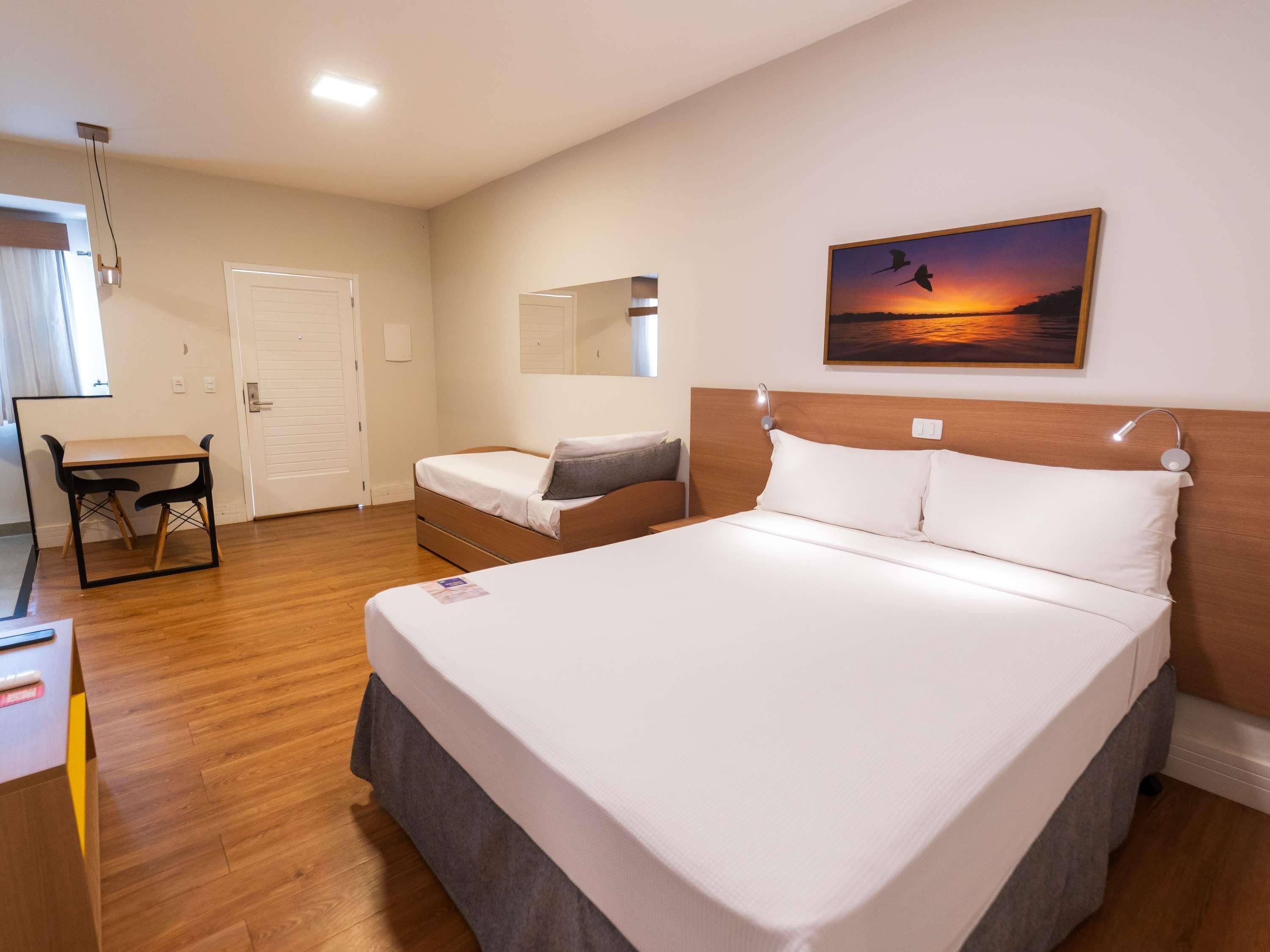 A hotel room with a bed, a desk, and a chair.