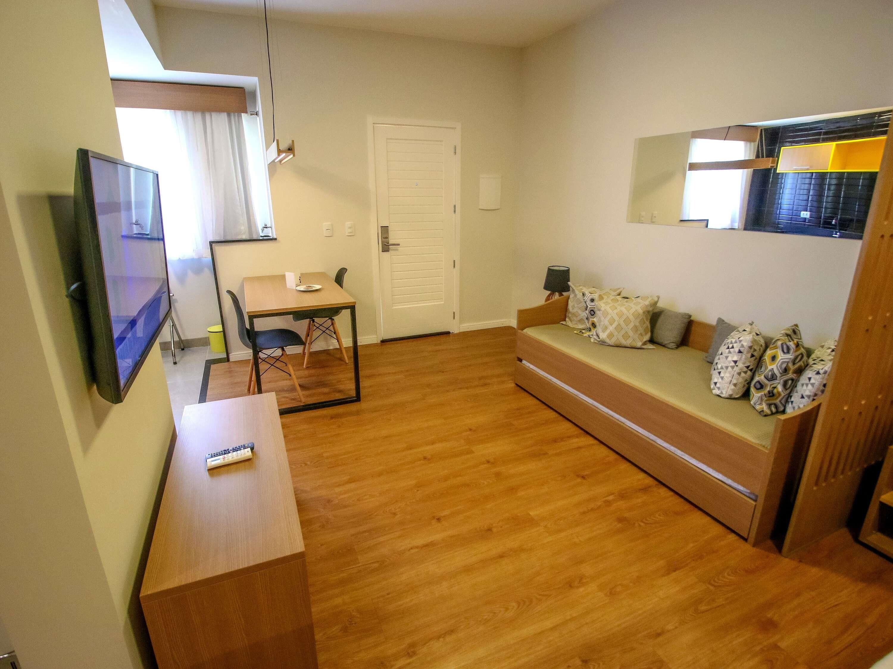 A compact living space with a sofa, a small table, a TV, and a door.