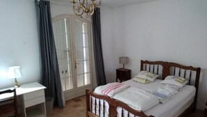 A bedroom with a wooden bed, a desk with a lamp, a chair, and a wardrobe with a mirror. - Pretty villa on a hill on the edge of the forest (La Crau)