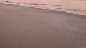 Une plage avec un ciel dégagé et une lune visible.