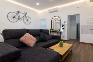 A modern living room with a dark grey sofa, a wooden coffee table, and a bicycle mounted on the wall.