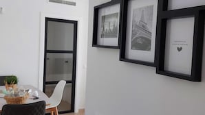 A modern dining area with a white table, black chairs, and framed black-and-white photographs on the wall. - MARINA BEACH APARTMENT (Oropesa del Mar)