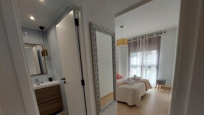 A hotel room with a bathroom, a bed with towels, a bedside table, and a window with curtains. - MARINA BEACH APARTMENT (Oropesa del Mar)