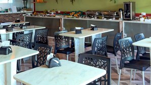 A restaurant with multiple tables and chairs, a counter with food and drinks, and hanging plants on the wall. - Pousada Tropical Maragogi (Maragogi)