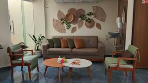 A living room with a sofa, two armchairs, a coffee table, and a small side table. There are decorative wall hangings and a potted plant. - Pousada Tropical Maragogi (Maragogi)